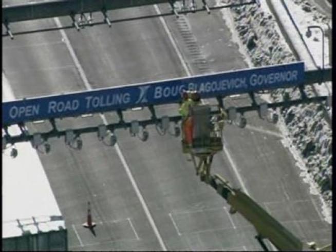 Workers cover up the toll plaza signs at I-355 and Boughton Road, excising Blagojevich's name.