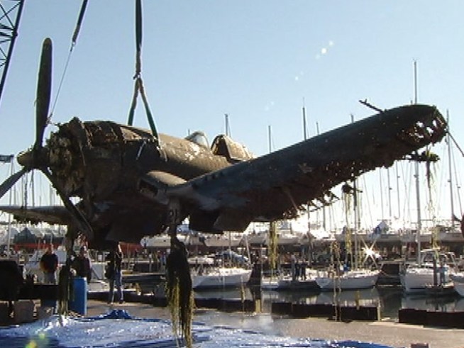 A Navy Corsair F-21 airplane is lifted out of <a title=