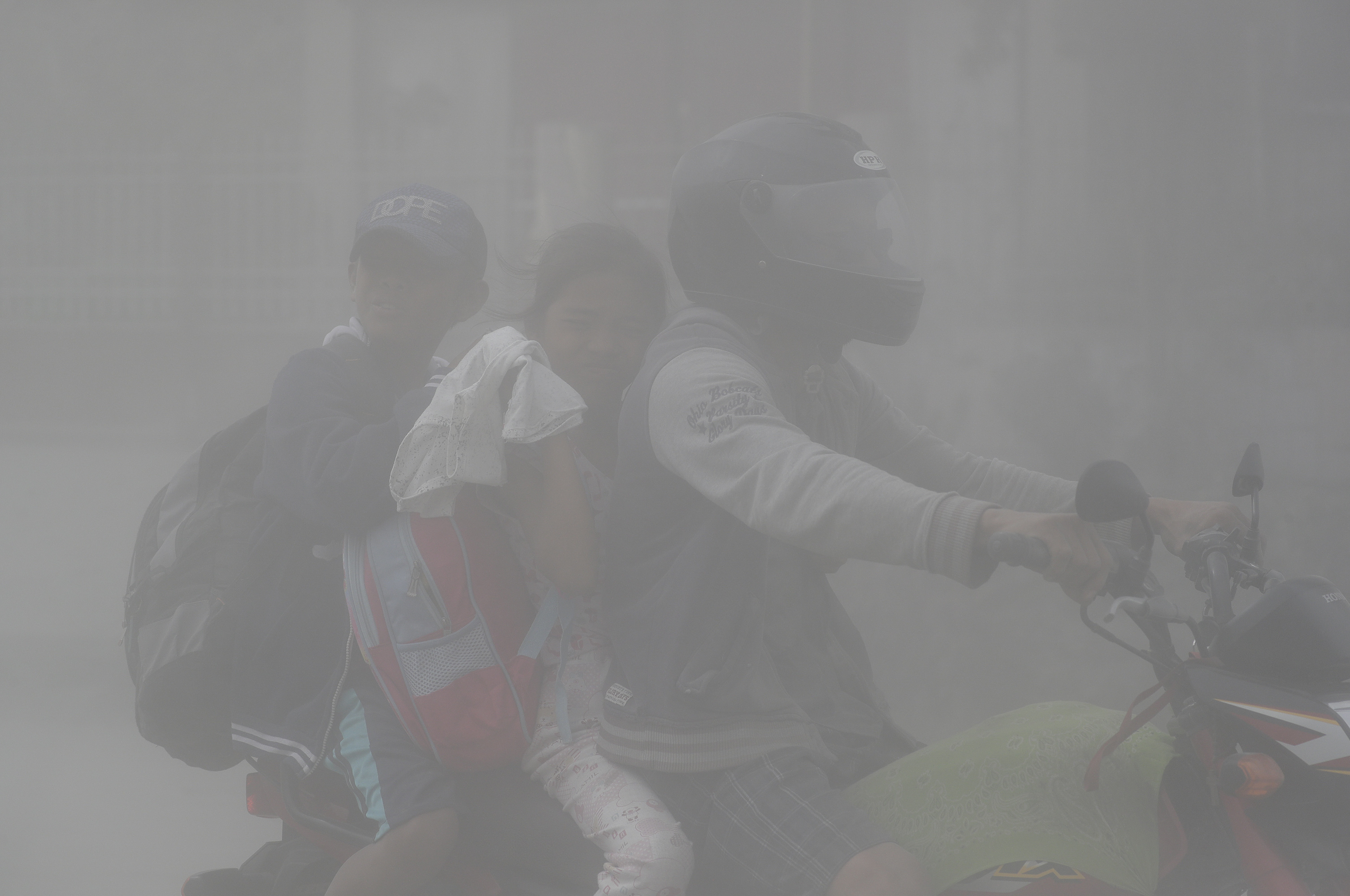 A family rides through clouds of ash as they evacuate to safer grounds in Lemery, Philippines,  Jan. 13, 2020. Red-hot lava gushed from the volcano after a sudden eruption of ash and steam that forced residents to flee and shut down Manila’s airport, offices and schools.