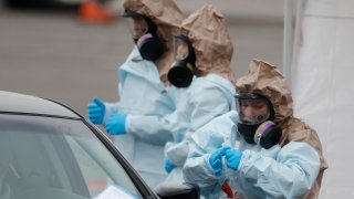 Colorado National Guard medical personnel perform coronavirus test on a motorist at a drive-through testing site outside the Denver Coliseum Saturday, March 14, 2020, in Denver. Officials planned to administer 150 tests but the line of vehicles wrapped around three city blocks. For most people, the new coronavirus causes only mild or moderate symptoms. For some it can cause more severe illness.