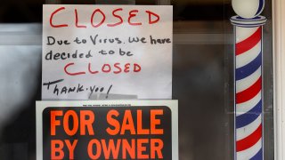 In this April 2, 2020, file photo, "For Sale By Owner" and "Closed Due to Virus" signs are displayed in the window of Images On Mack in Grosse Pointe Woods, Mich.