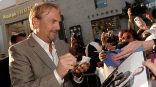 Kevin Costner looks down at a photo of himself from the film "Bull Durham" as he signs autographs in Los Angeles.