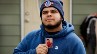 Omar Martinez holds a photo of his father, Jose Gabriel Martinez, as he stands in front of their home