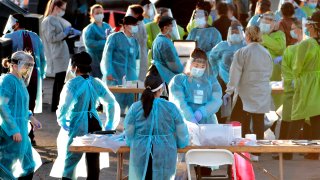 In this June 27, 2020, file photo, medical personnel prepare to test hundreds of people lined up in vehicles in Phoenix's western neighborhood of Maryvale.