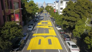 An aerial photo shows a giant street mural reading "Black Lives Matter" in San Francisco.