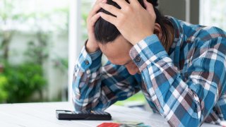 Photo illustration of a young man overwhelmed by credit card debt.