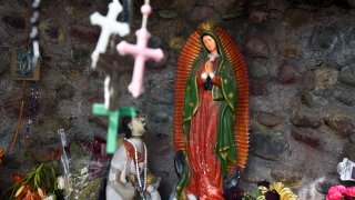 In this Oct. 22, 2018, file photo, a statue of Our Lady of Guadalupe is among items left by worshippers in a shrine at El Santuario de Chimayo in the hispanic village of Chimayo, New Mexico. The chapel, a National Historic Landmark, is famous for the story of its founding and as a contemporary pilgrimage site.