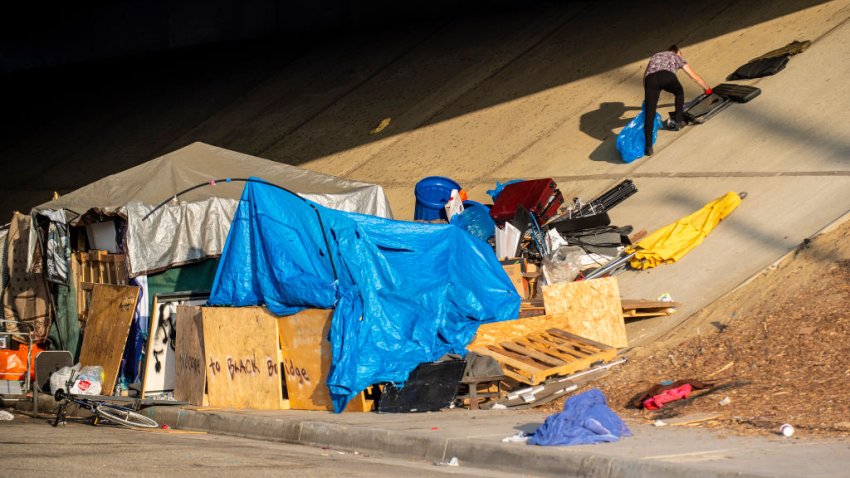 PLACENTIA, CA – AUGUST 27: A woman packs her belongings into a bag at the homeless encampment site on West Crowther Avenue under the 57 freeway in Placentia on Tuesday morning, August 27, 2019. Various agencies from the city of Placentia along with workers from Caltrans and the California Highway Patrol arrived before sunrise to clean up and power-wash the homeless encampment site. The homeless living at the site will be allowed to return once the cleanup is completed and clearance is made for pedestrians on the sidewalk. (Photo by Mark Rightmire/MediaNews Group/Orange County Register via Getty Images)