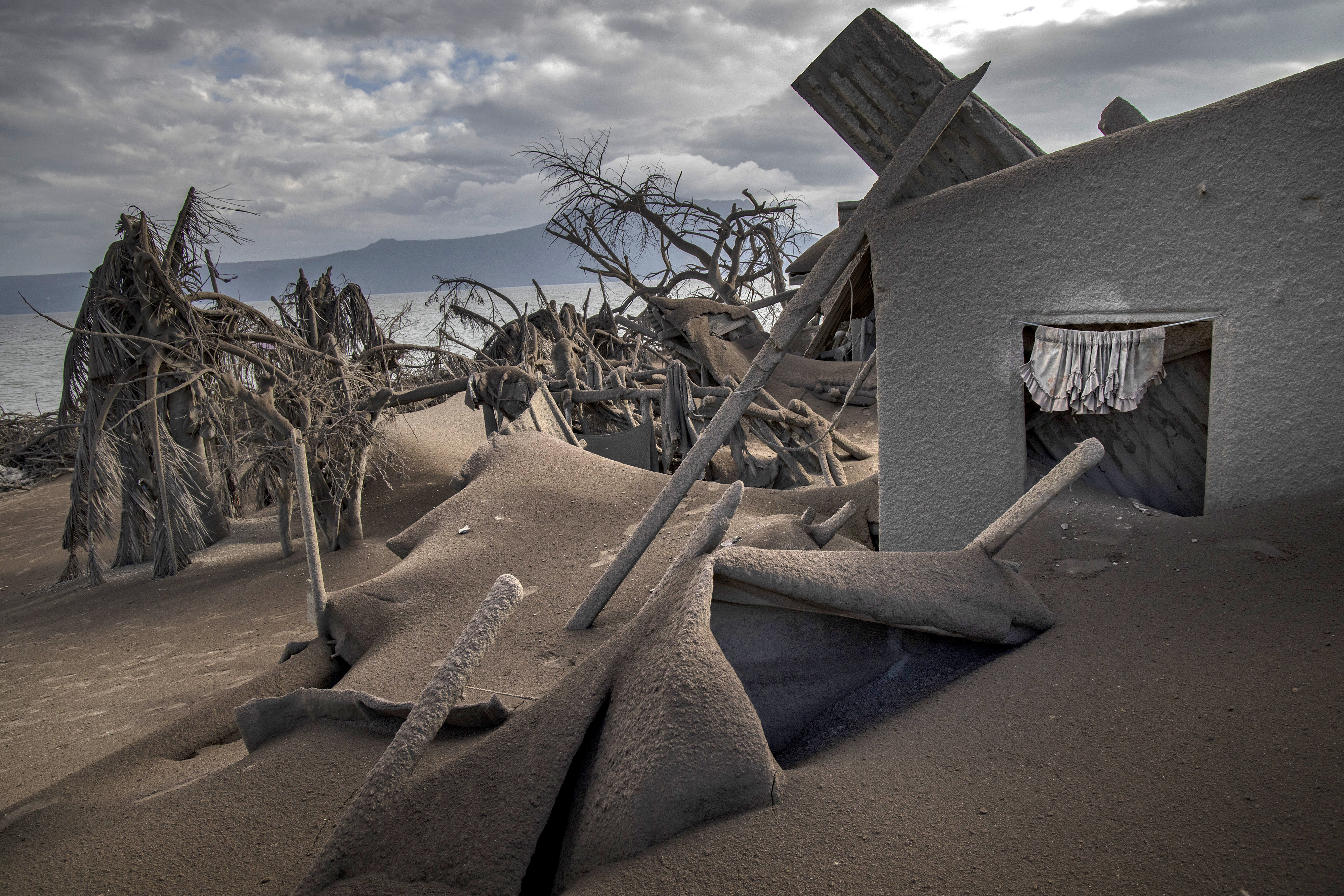 Houses near Taal Volcano’s crater is seen buried in volcanic ash from the volcano’s eruption on Jan. 14, 2020, in Taal Volcano Island, Philippines.