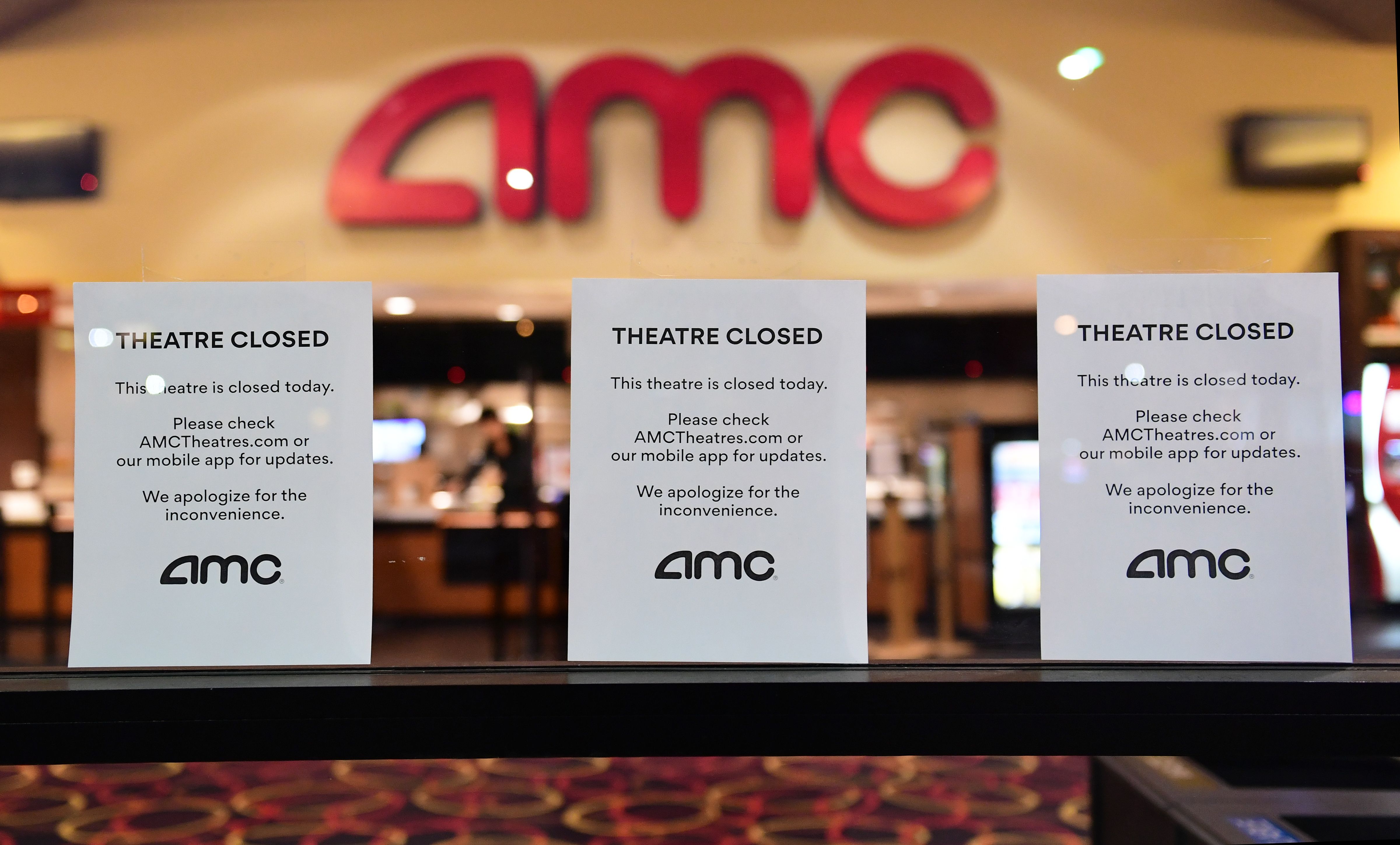 "Theater Closed" signs are posted in front of an AMC movie theater