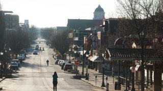 A woman stands in the middle of Kirkwood Avenue near Indiana University just a few hours after Indiana Governor Eric Holcomb announced a "stay at home" order during the Covid-19/Coronavirus emergency in Bloomington, Ind. Seven Hoosiers have already died from the virus, and over 200 have been sickened. Indiana University sent students home for the semester, and is teaching classes virtually