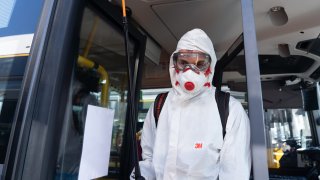 A sanitation worker disinfects public transportation