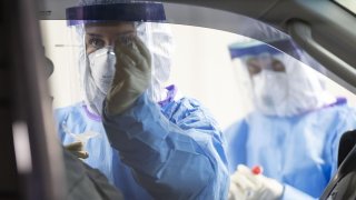 In this March 26, 2020, file photo, Senior Airman Serena Nicholas administers a coronavirus test to a first responder in a vehicle on Chicago's Northwest Side.