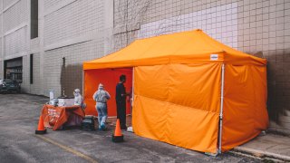 Staff members inside the outdoor facility outside of Innovative Express Care on Chicago's Northwest Side, in Chicago, United States, on March 30, 2020. Dr. Rahul Khare and his team have been testing patients for COVID-19 at an outdoor facility set up in the parking lot of Innovative Express Care on Chicagos northwest side. They have tested hundreds of patients and confirmed 28 cases and counting of COVID-19. Testing is done inside their bright orange tent, or patients can be tested while sitting in their cars
