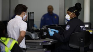 TSA agent in mask at LAX speaks with traveler in mask.