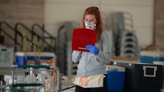 A worker wearing a face mask prepares an internet order for customers of the Bloomington Community Farmers' Market where food is being distributed in a drive-thru arrangement at the Switchyard Pavilion