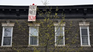A building tenant hangs a sign from his roof in the Crown Heights neighborhood during a rent strike on May 1, 2020 in New York City.
