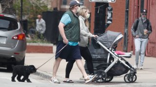 People wearing face masks walk on a street in Chicago