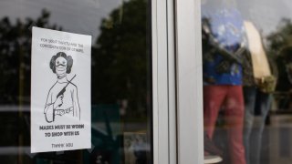 A sign asking patrons to wear a mask while shopping hangs in the window of a store in the Plaza Midwood neighborhood of Charlotte, North Carolina, U.S., on Friday, May 8, 2020.