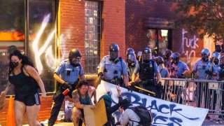 Protester crouching on the ground with police behind them