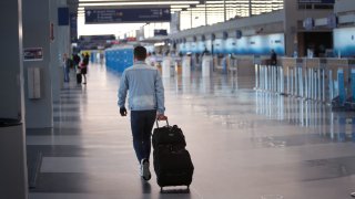 In this April 2, 2020, file photo, a traveler arrives at a nearly-deserted passenger terminal at O'Hare International Airport in Chicago, Illinois.