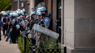 Police stand guard as demonstrators take part in a protest in Uptown