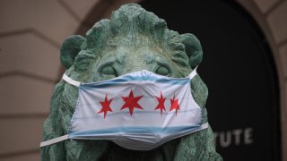 A lion sculpture in front of the Art Institute wears a mask