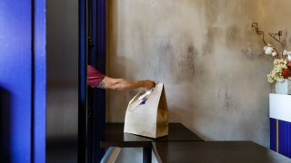 A customer receives their order through a take-out window at ROOH Chicago