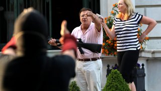 Armed homeowners standing in front of their house along Portland Place confront protesters as they march to Mayor Lyda Krewson's house on Sunday, June 28, 2020, in the Central West End in St. Louis.