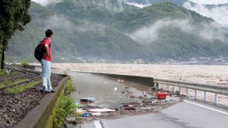 A man looks at the overflowing kuma river caused by heavy rain in Yatsushiro, Kumamoto prefecture on July 4, 2020.