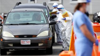 This May 15, 2020, file photo shows medical professionals at a drive-thru coronavirus testing site at CHA East Cambridge Care Center in Cambridge, Massachusetts.