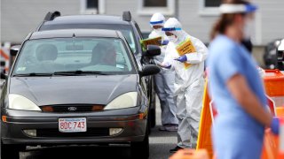 This May 15, 2020, file photo shows medical professionals at a drive-thru coronavirus testing site at CHA East Cambridge Care Center in Cambridge, Massachusetts.
