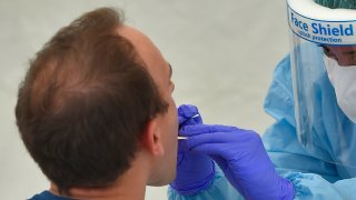 A health worker uses a swab to collect samples at a testing center for coronavirus