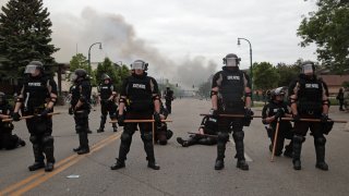 Police officers block a road on the fourth day of protests in Minneapolis
