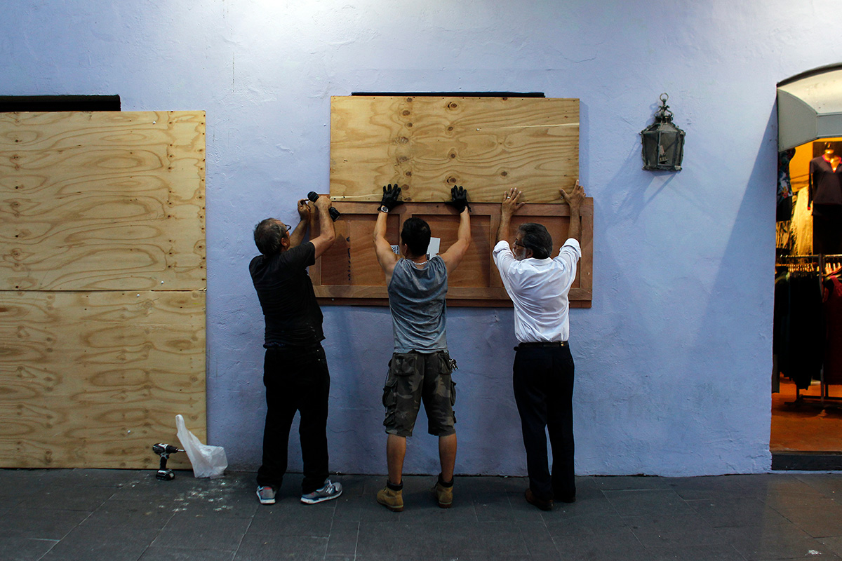 People board up windows of a business in preparation for the anticipated arrival of Hurricane Maria in San Juan, Puerto Rico on September 18, 2017. Hurricane Maria has grown into a maximum-strength Category Five storm, US forecasters said Monday, as it was bearing down on the Caribbean island of Dominica.