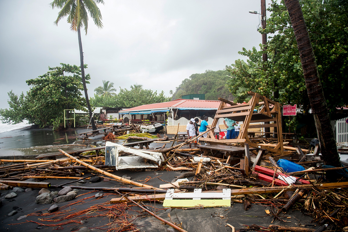 People stand next to debris at a restaurant in Le Carbet, on the French Caribbean island of Martinique, after it was hit by Hurricane Maria, on September 19, 2017.