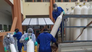 In this May 20, 2020, file photo, medical workers offload cylinders of oxygen at the Donka public hospital where coronavirus patients are treated in Conakry, Guinea. Before the coronavirus crisis, the hospital in the capital was going through 20 oxygen cylinders a day. By May, the hospital was at 40 a day and rising, according to Dr. Billy Sivahera of the aid group Alliance for International Medical Action.