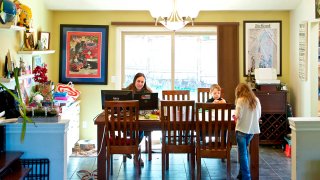 Kim Borton, left, works from home while her children Logan Borton, center, age 6, and Katie Borton, age 7, work on an art project in Beaverton, Ore.