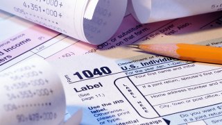 A stock photo shows income tax forms, receipts and a sharpened pencil.