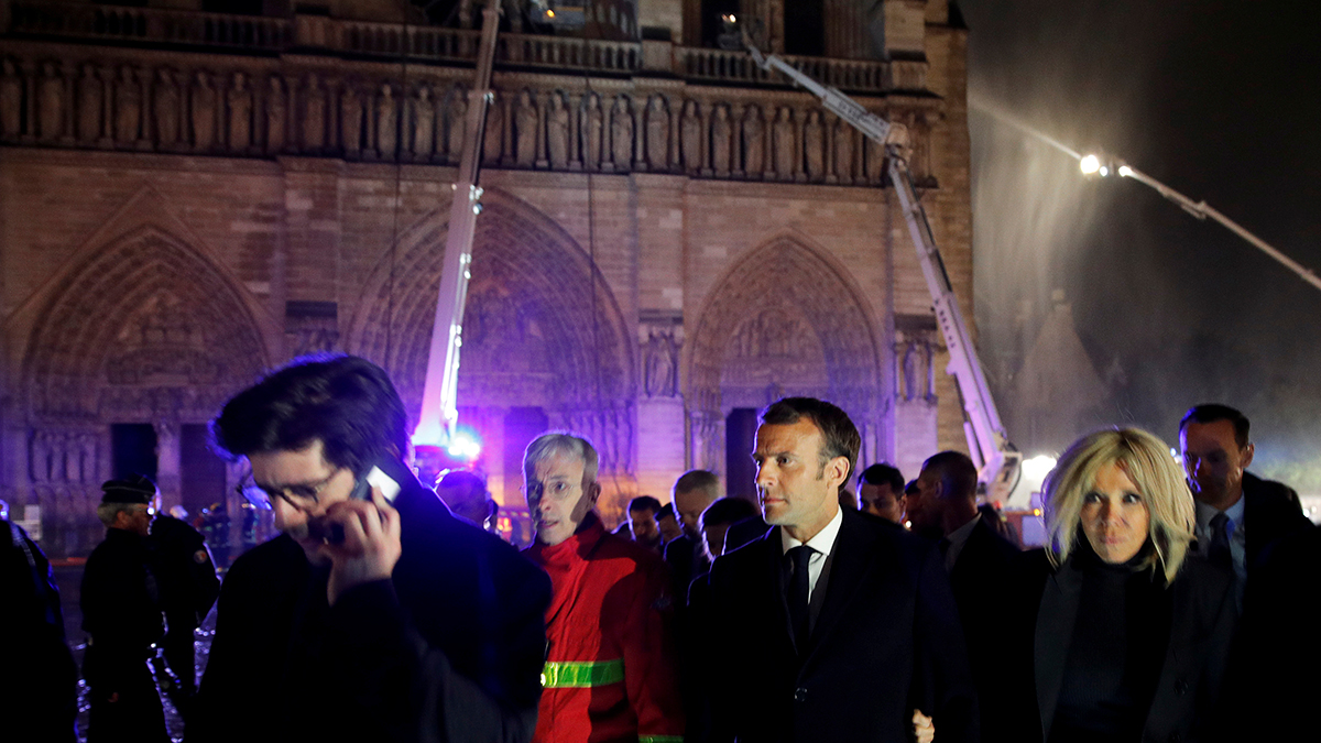 French President Emmanuel Macron, center, and his wife Brigitte walk away from Notre Dame cathedral in Paris, Monday, April 15, 2019.