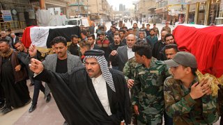 Mourners carry the flag-draped coffins of two fighters of the Popular Mobilization Forces who were killed during the US attack on against militants in Iraq, during their funeral procession at the Imam Ali shrine in Najaf, Iraq, Saturday, March 14, 2020.