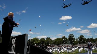 President Donald Trump applauds as Army helicopters fly over and West Point cadets toss their caps into the air at the end of commencement ceremonies on the parade field, at the United States Military Academy in West Point, N.Y., Saturday, June 13, 2020.