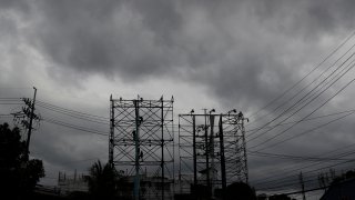 Dark clouds envelop the skies as workers fold a billboard to prepare for the coming of typhoon Vongfong in Manila, Philippines Thursday May, 14, 2020.