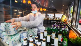 Sarah Rivas, an employee at Annie's Paramount Steakhouse in the Dupont Circle area of Washington, D.C., arranges a display of toilet paper and liquor for carry out orders Monday, April 13, 2020.