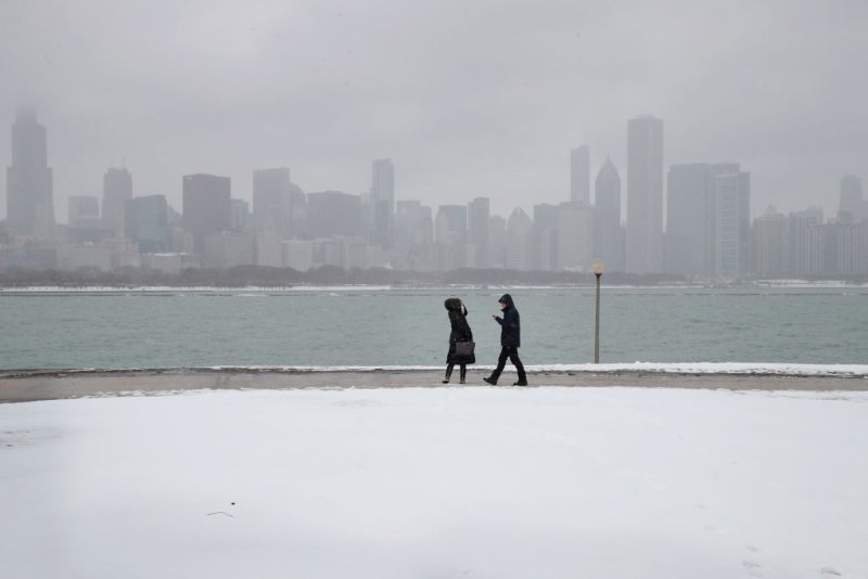 människor går längs en snötäckt lakefront nära centrala Chicago.