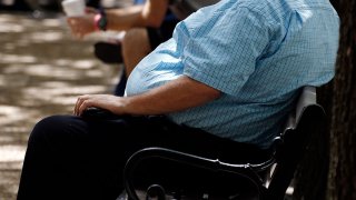 In this Thursday, Sept. 4, 2014, file photo, an overweight man rests on a bench in Jackson, Miss.