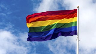 A rainbow flag on a pole, flapping in the wind.