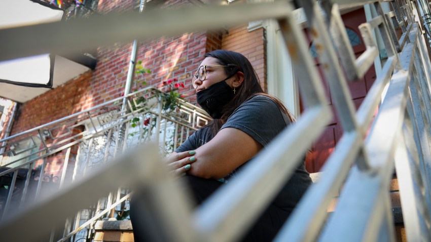 Natalia Afonso, 27, an international student from Brazil at Brooklyn College, sits on a stoop outside her home during an interview, Thursday, July 9, 2020, in New York. Afonso, who is studying teaching education and finished her first semester this spring, said she has lived in the U.S. for 7 years and "I don't see myself moving back to Brazil at this point.