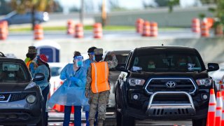 A National Guard troop directs cars as people are tested by healthcare workers at the COVID-19 drive-thru testing center at Hard Rock Stadium in Miami Gardens as the coronavirus pandemic continues on Sunday, July 19, 2020. (David Santiago/Miami Herald/Tribune News Service via Getty Images)