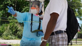 Workers check in residents at a mobile COVID-19 testing site set up on a vacant lot